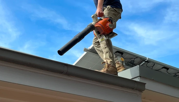 Guy on top of roof leaf blowing cleaning gutters