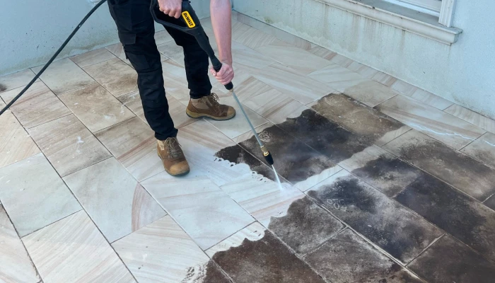 Man pressure washing tiles